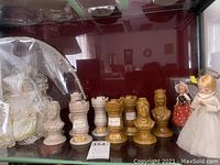Front view of eight chess piece decanters and three dolls, some dolls wrapped in protective material.