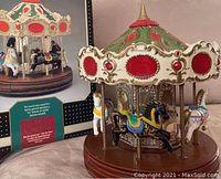 Carousel figurine showing painted horses, red and gold canopy, and wooden base.