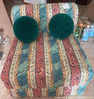 Front view of the sleeper chair showing the patterned fabric and two round green pillows on seat back.