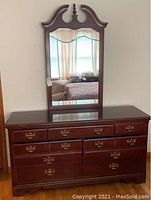 Front view of Thomasville 7-drawer dresser with mirror showing mahogany finish and brass ornate drawer handles.