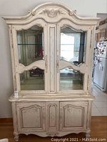 Front view of off-white Thomasville china cabinet with double glass doors and ornate carved details.