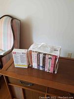 Photo of a set of classic TV show DVDs in plastic case alongside miscellaneous VHS tapes placed on wooden table.