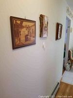 Three framed signed wood art pieces on a wall showing banana leaf, Alaskan wood theme and a wood inlay scene