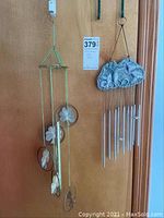 Two hanging wind chimes with hooks on display against a wooden door