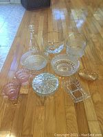 Overview of all 12 glass bowls and dishes arranged on wooden floor.