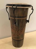 Wooden bongo drum showing carved decorative motif and tuning mechanisms