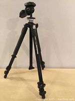 Front angle view of a black Manfrotto tripod showing extendable legs and mounting head.
