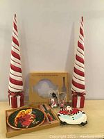 Photo showing two tall red and white spiral Christmas trees, boxed 10-inch cake plate with server, Santa Claus dish, and several Christmas ornaments.