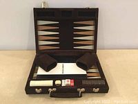 Travel backgammon game shown open with playing board inside case, two dice cups, dice, and chips visible