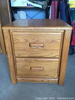 Front view of oak side table showing two drawers with wooden handles and rounded edges