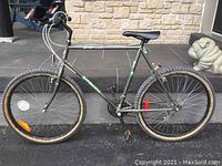 Side profile of a metallic gray-green Gemini Supercycle 18 speed bicycle with knobby tires, black seat, reflectors on wheels.