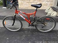 Side view of orange Supercycle 18 speed mountain bike showing frame, tires, handlebars, saddle, and suspension.