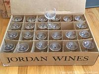 24 clear wine glasses neatly arranged in a cardboard box with dividers, labeled 'Jordan Wines'.