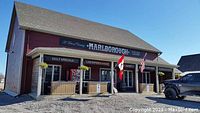 Photo showing the exterior of Marlborough Pub, a red building with a porch, signage for daily specials and live entertainment, with flags displayed.