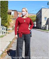 Model wearing the red Elara Tie Top outdoors, showing long sleeves, front seam and tie detail at hem.