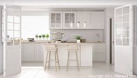 Modern white kitchen with island, bar stools, glass-front cabinets, pendant lights, and stainless faucet