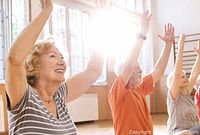 Seniors participating in group exercise session in a room with large windows