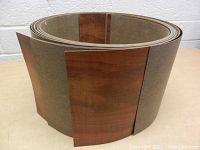 Large roll of wood laminate veneer showing wood tone finish and backing material