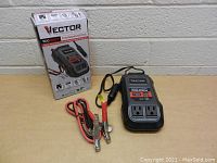 Vector 500 watt power inverter unit with attached cables and original box, shown on a white table against a brick wall background.