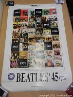 Front-facing photo of large Beatles poster with multiple albums shown from years 1963 to 1970.