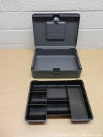 Opened grey metal cash box showing interior compartments and removable tray for organizing coins and bills.
