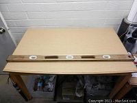 Top-down view of the full wooden Stanley spirit level laid flat on a wooden table showing the three spirit vials and handle cutouts.