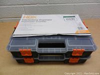 Two stacked HDX organizers with clear lids, gray bases, and orange latches shown with packaging label on top.
