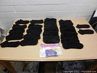 20 pairs of black women's ankle socks laid out on a wood table with original Hanes 10 pack plastic packaging included in the lot.