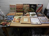 Photo showing 15 cooking and food books arranged on a table with titles visible including Earth Medicine Earth Food, The Wildflower Book, The Herb Book, and Spices.
