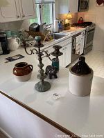 Kitchen counter with 12-inch and 6-inch crocks, 17-inch metal candelabra, and small elephant figurine arranged together