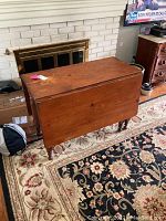 Front view of mid-century pine drop side table showing closed foldable leaves, visible surface wear, and turned legs.