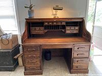 Front view of vintage roll top desk showing drawers and open roll top compartments.