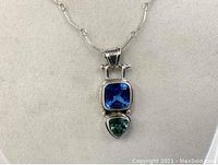 Front view of the pendant necklace showing the blue and green stones with sterling silver setting and chain detail.