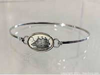 Front view of the slender sterling silver bangle bracelet, showing detailed ship engraving on the oval centerpiece.