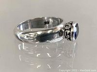 Silver ring with a deep oval purple stone set in bezel setting showing inside band hallmark '925' indicating sterling silver.