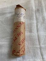 Photo of a rolled coin wrapper labeled '1945 S' containing 50 wheat pennies minted in San Francisco.