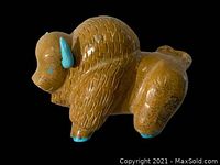 Photo of a light brown buffalo fetish carved with texture and turquoise-colored horns and hooves.