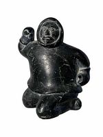 Front view of the black stone carving of the Inuit hunter in a traditional parka, showing detailed facial features and raised right hand.