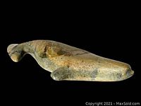 Side view of the carved stone whale showing the form and color variation in the stone.