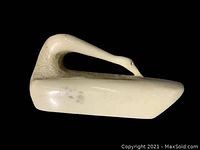 Front view of off-white carved swan sculpture against black background