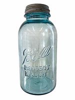 Front view of antique 1/2 gallon Ball Mason jar in aqua glass with original zinc lid, showing embossed logo and bubbles in the glass.