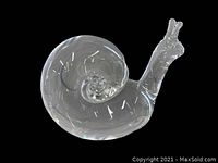 Clear glass snail paperweight viewed from an angle showing the front and spiral shell.