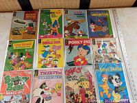Photo showing all 12 vintage comic books spread out, titles and characters visible including Mickey Mouse, Bugs Bunny, Donald Duck, Porky Pig, and more, with visible plastic sleeves.