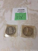 Two Canadian silver dollar coins in protective plastic sleeves showing aged patina and both sides.