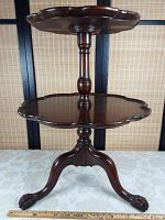 Full frontal view of two-tier walnut table showing pie crust scalloped edge tiers and lion's paw feet.