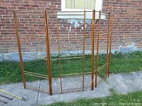 Full view of large expandable wooden drying rack with three hinged sections and wood rods, showing overall structure, outside setting.