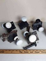 Five antique box locks with white porcelain door knobs arranged on a surface alongside a ruler for scale.