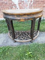 Front view showing semi-circular shape, carved legs, skirt, and geometric lattice lower shelf on the wooden antique table