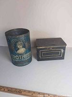 Both tins placed side by side showing overall appearance and scale with a ruler for size reference