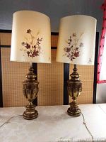 Two heavy brass lamps with floral Dornbush shades displayed side by side.